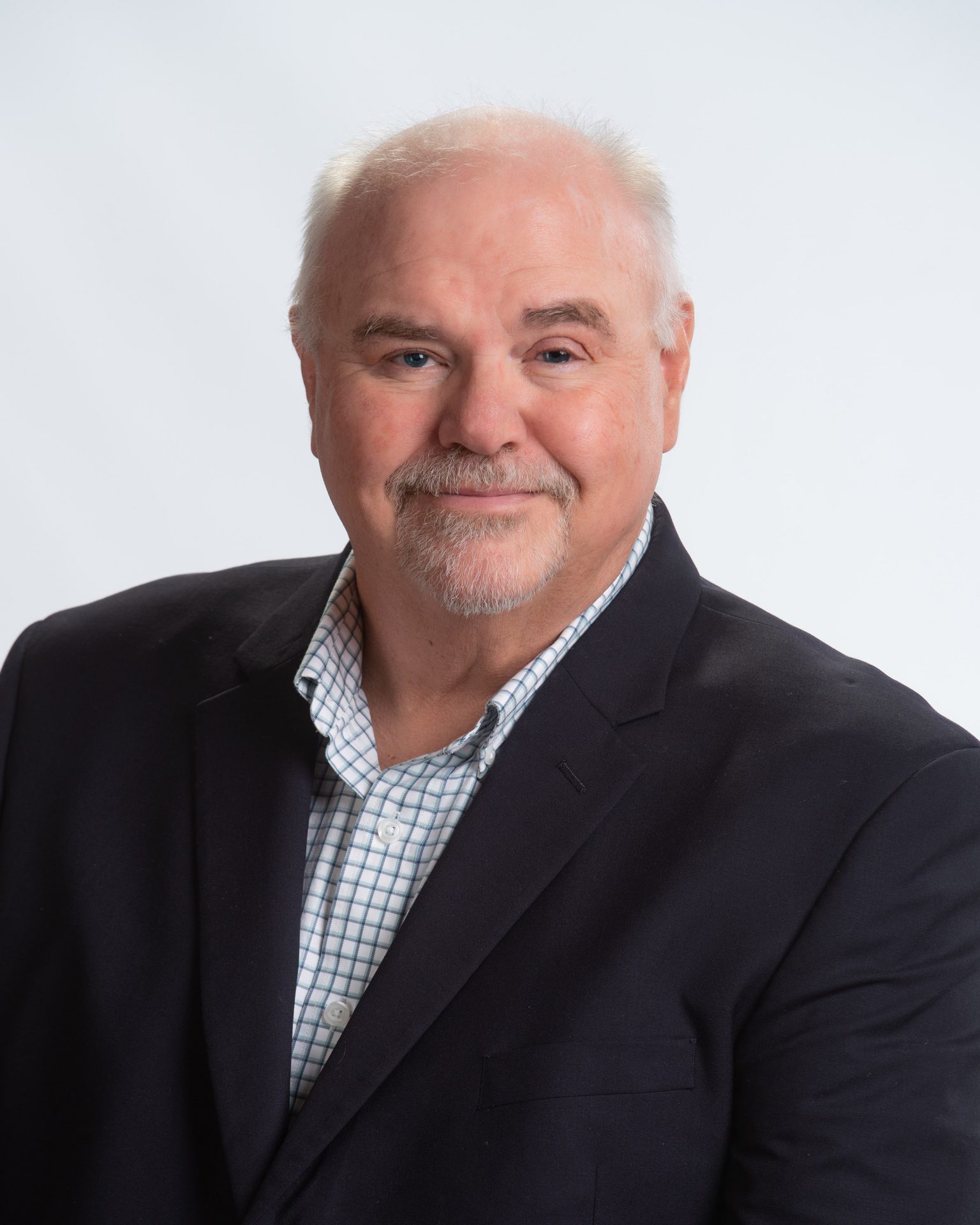 Man with white hair wearing suit indoors and is a farm land appraiser from Premier Farm Credit in northeast Colorado and Nebraska