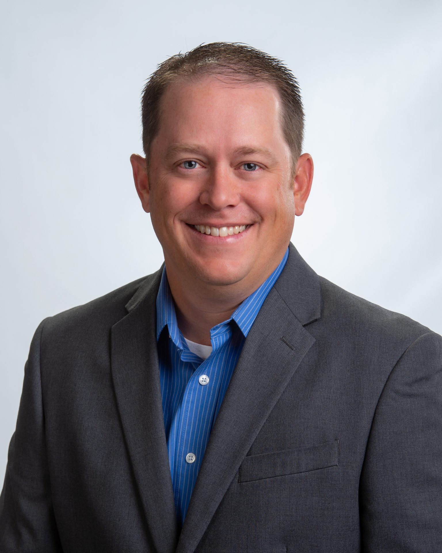 Man wearing a suit smiling at the camera inside of Premier farm Credit, specializing in farm ag insurance and crop insurance such as crop-hail and PRF policies and life insurance