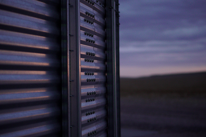 Grain bin by a farm shed in Nebraska during a sunset, on land financed by Premier Farm Credit, specializing in agriculture equipment loans